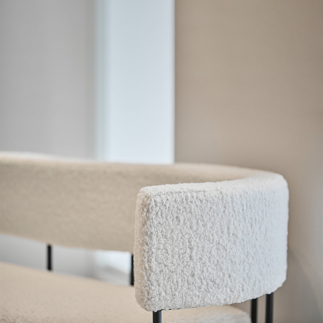 Cozy cream boucle upholstery with sleek black metal legs, creating a modern, stylish accent for any space.