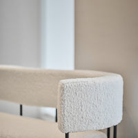 Cozy cream boucle upholstery with sleek black metal legs, creating a modern, stylish accent for any space.