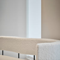 Textured white upholstered chair with a modern design, featuring a soft, cozy finish and sleek black metal accents.