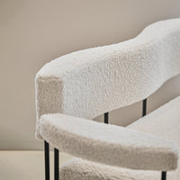 Textured white upholstery on a modern chair with black metal frame and soft, curved armrests.