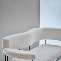 White curved sofa with a textured, fluffy finish, set against a minimalist light gray background.
