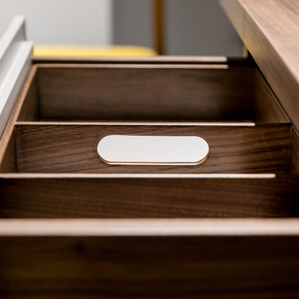 Close-up of wooden drawer interior featuring a rich walnut finish and a sleek white drawer pull.