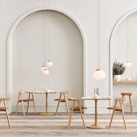 Sleek, neutral tones with warm wood accents and soft, round lighting create a modern, inviting dining atmosphere.