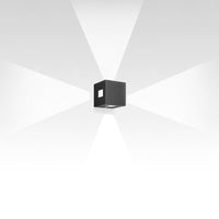 Black cube wall light with a sleek modern design, casting a soft white spotlight pattern on a light background.