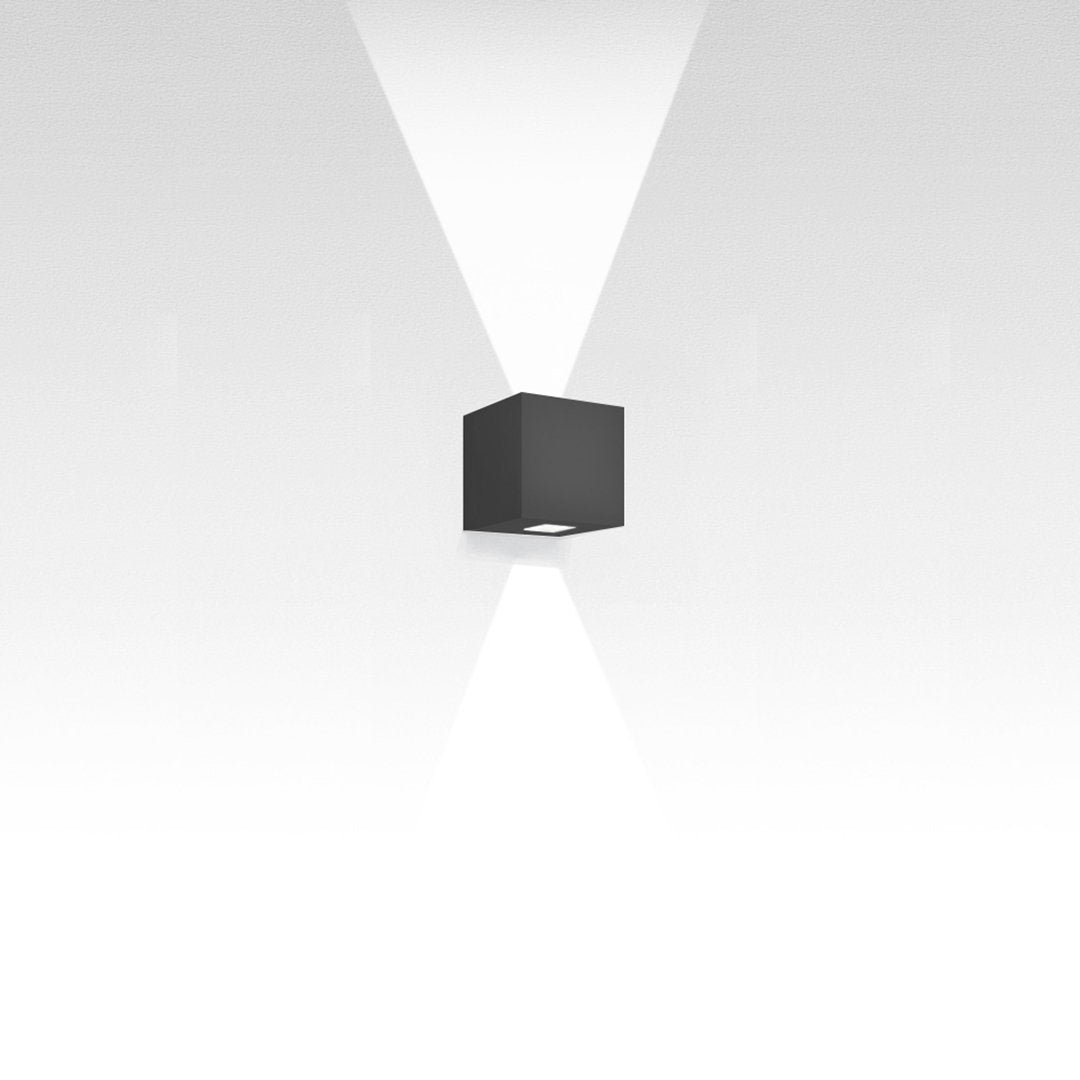 Black cube wall light with sleek, modern design; emits two beams of light creating a geometric pattern against a white background.