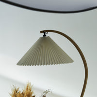 Off-white pleated lamp shade with a curved wooden base; elegant and modern design. Perfect for minimalist decor.