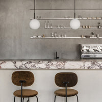 Modern bar with a textured gray wall, white globe pendant lights, and a marble countertop featuring soft pink and white patterns.