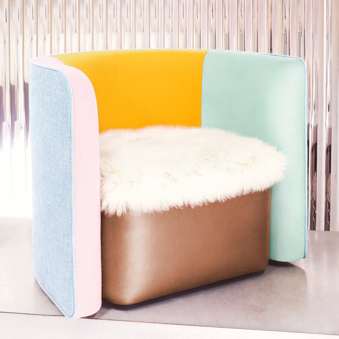 Colorful modern chair featuring vibrant yellow, pastel blue, pink, and earthy brown accents with a fluffy white seat cushion.