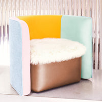 Colorful modern chair featuring vibrant yellow, pastel blue, pink, and earthy brown accents with a fluffy white seat cushion.