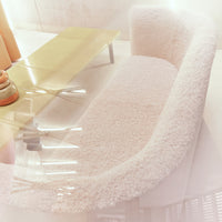 Soft, fluffy white curved sofa over a light wooden table, creating a cozy modern aesthetic.