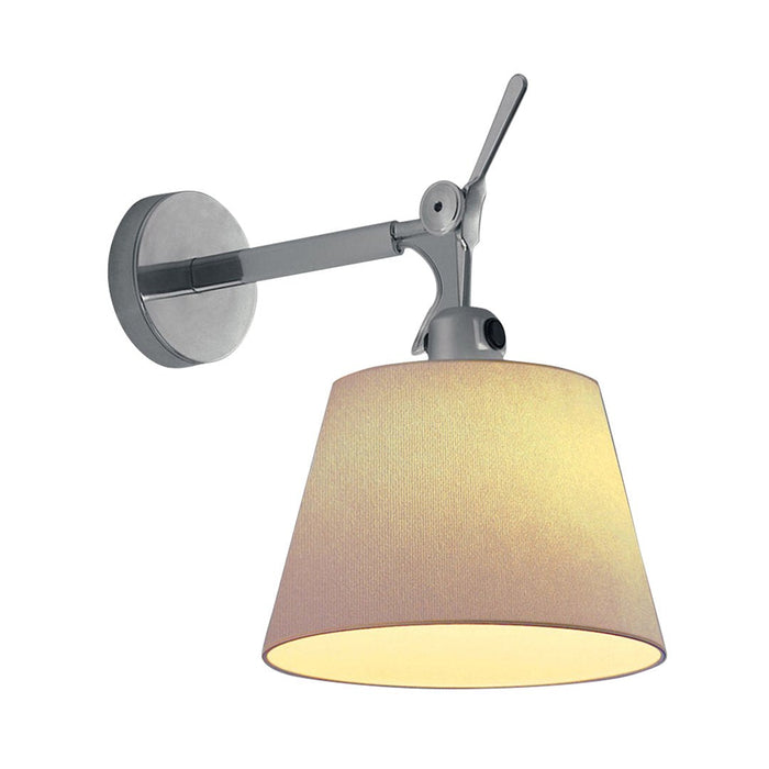 Modern wall lamp with a sleek silver arm and a soft beige fabric shade, creating a warm, inviting glow.