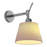 Wall-mounted lamp in brushed silver with a soft, cream-colored fabric shade. Elegant, minimalist design.