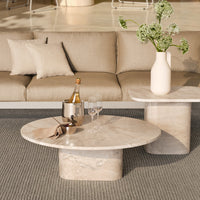 Marble coffee tables with a beige hue and soft patterns, paired with a neutral-toned sofa and textured rug.