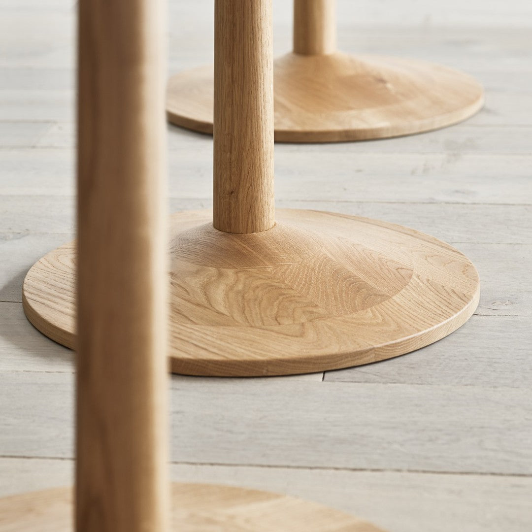 Natural wood table legs with a smooth, light oak finish and circular bases, showcasing subtle grain patterns.