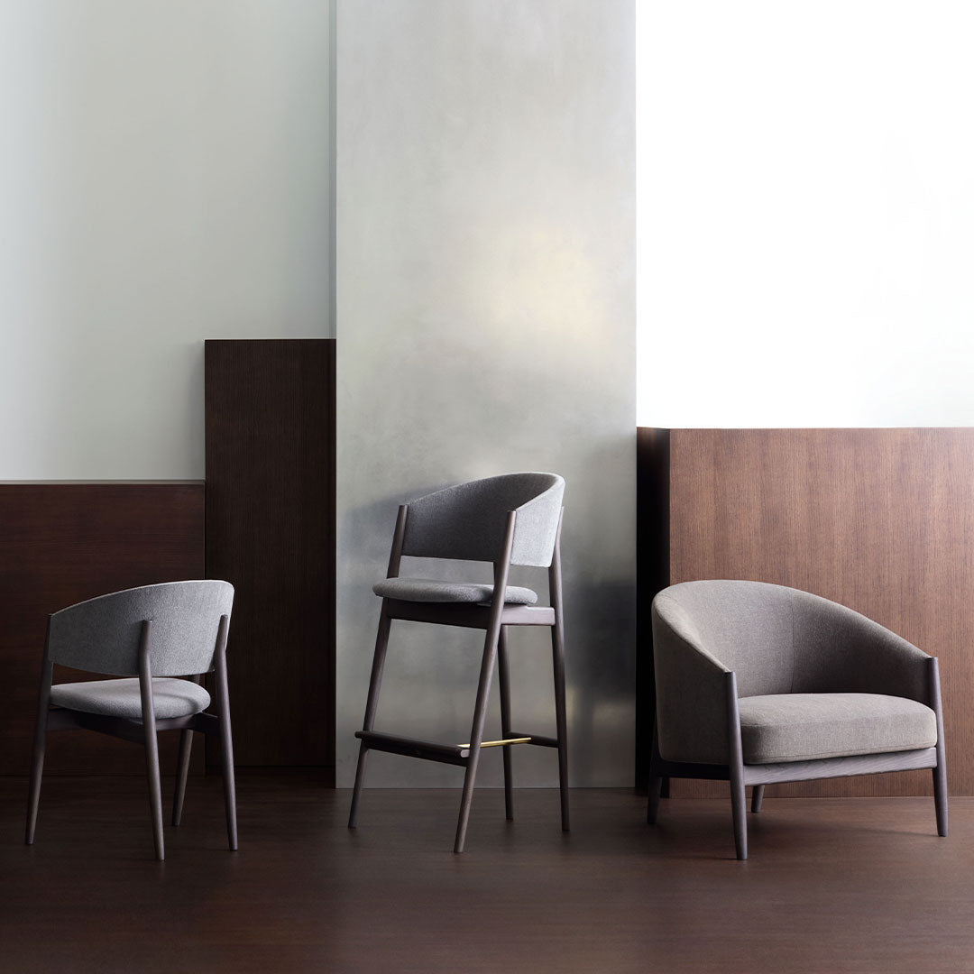 Gray upholstered chairs with sleek wood legs, set against a minimalist backdrop of muted colors and smooth textures.
