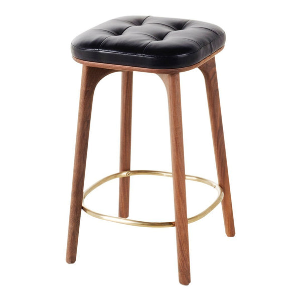 Black tufted leather stool with natural wood legs and a gold footrest. Elegant and modern design.