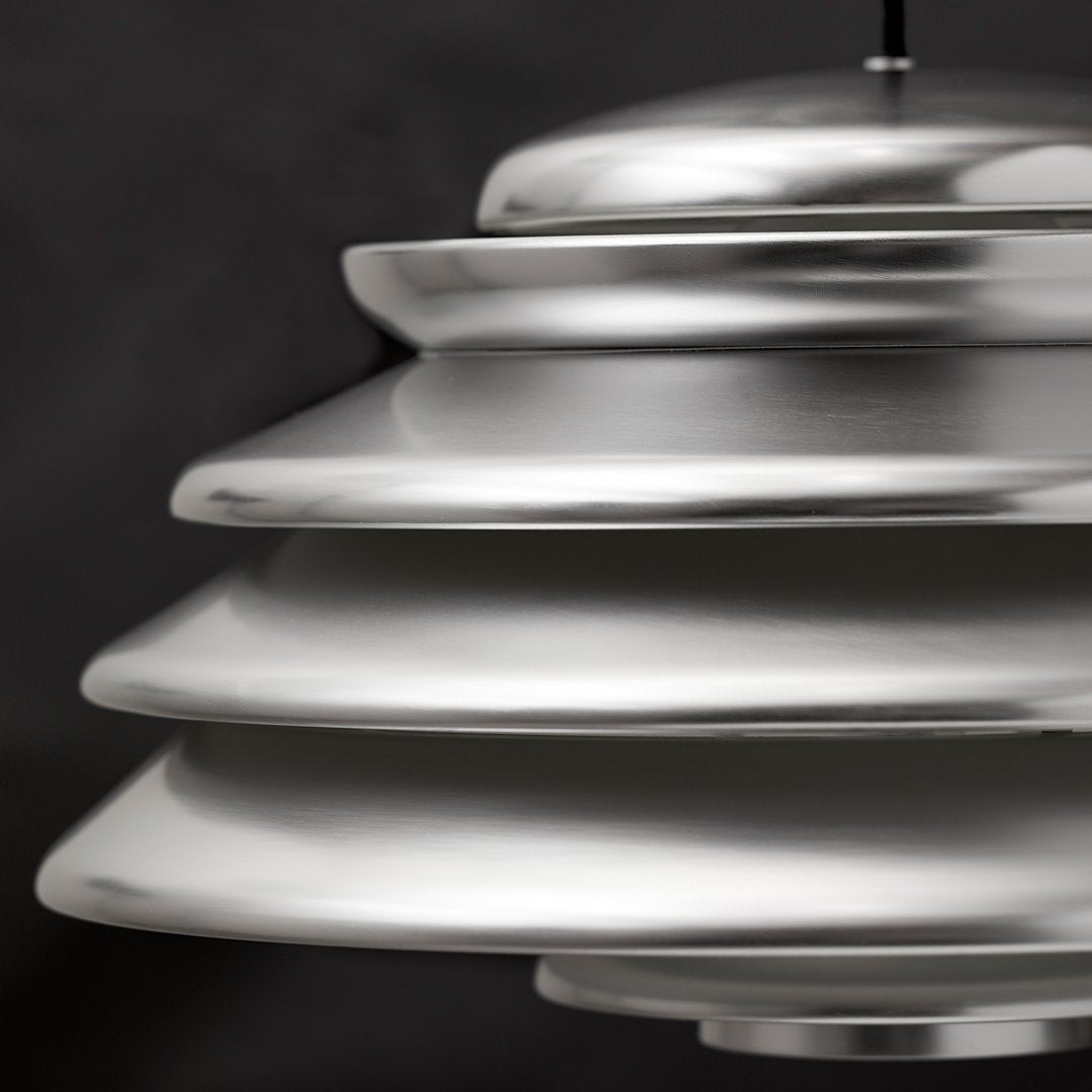 Silver layered pendant lamp with a sleek, modern design against a dark background.