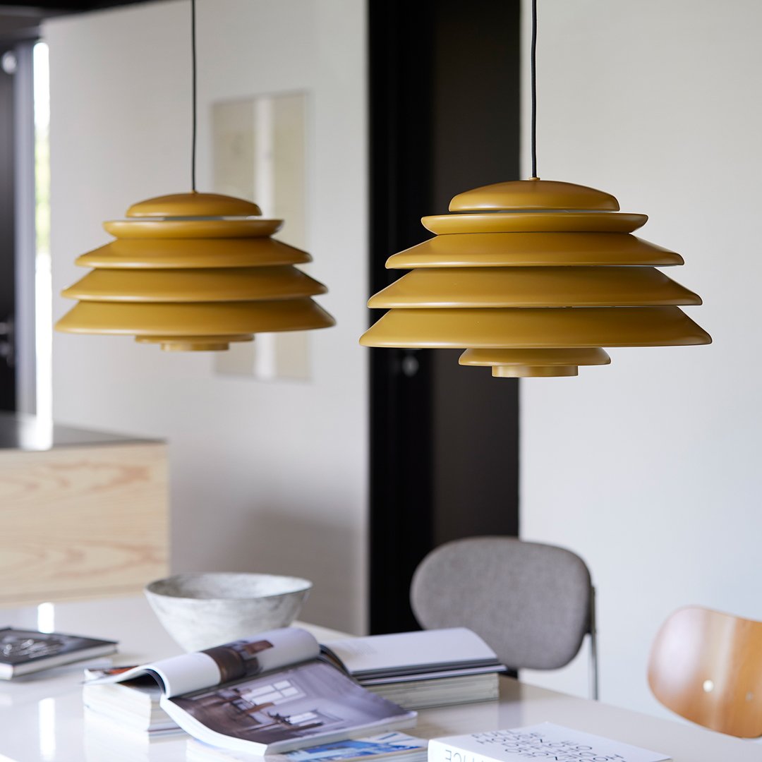 Two layered pendant lights in vibrant mustard yellow, creating a modern and stylish pattern in a contemporary setting.