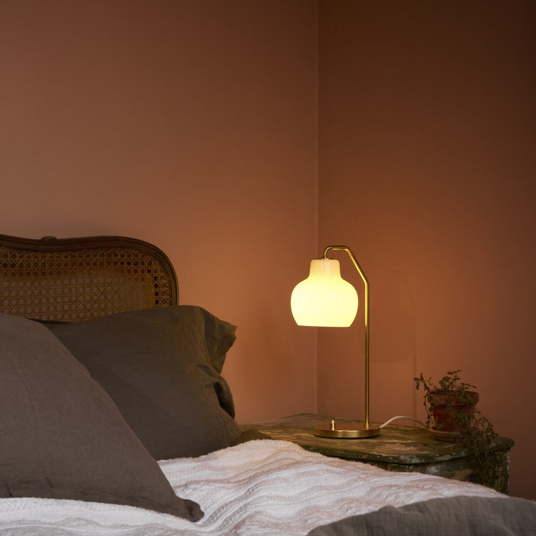 Bedroom scene with a lamp on a nightstand casting a warm glow.