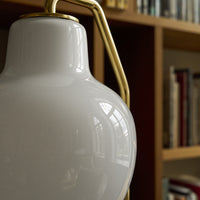 Close-up of a white lampshade with gold fixture against a blurred bookshelf background