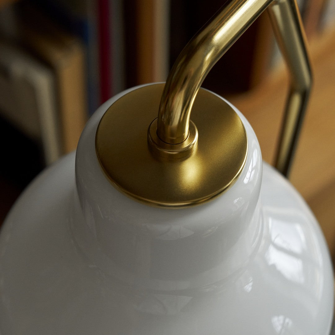 Close-up of a white lampshade with a gold fixture against a blurred background