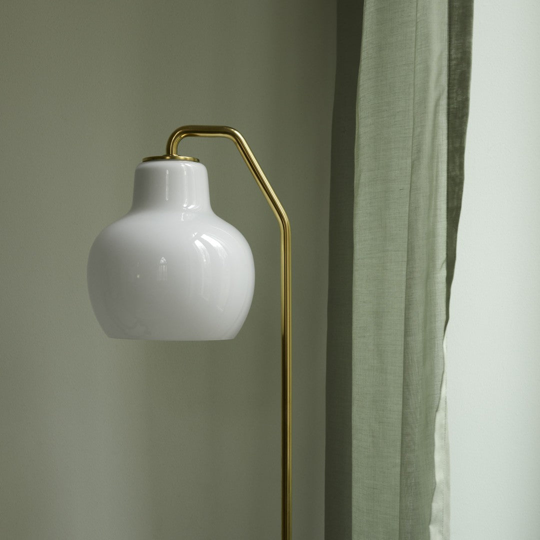 White floor lamp with gold arm against a neutral wall