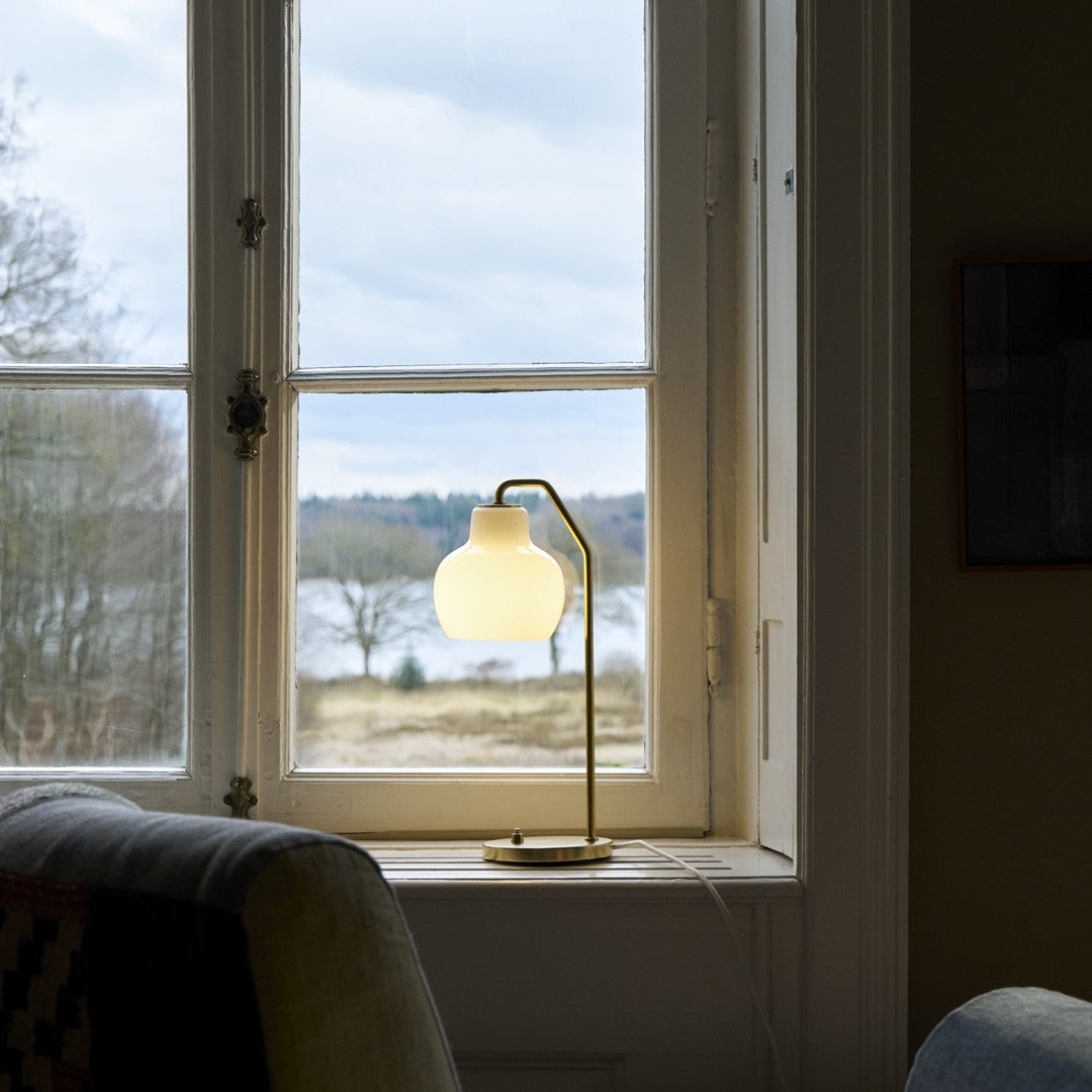 Table lamp on a windowsill with a view of trees and water outside