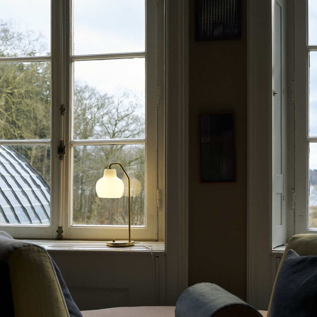 Living room with a lamp on a windowsill and a view of trees outside.