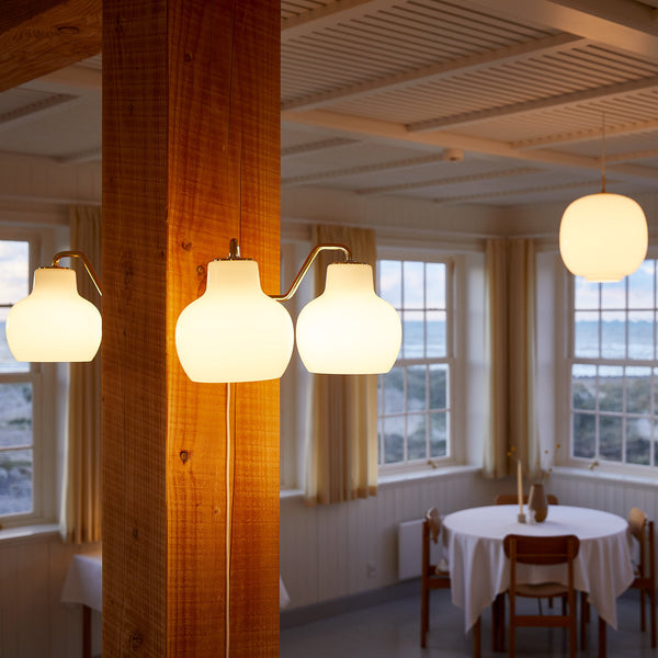 Elegant white pendant lights against wooden beams, creating a warm, inviting ambiance in a bright dining space.