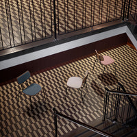 Three colorful chairs in blue, white, and pink on a patterned brown and beige floor. Modern design elements.