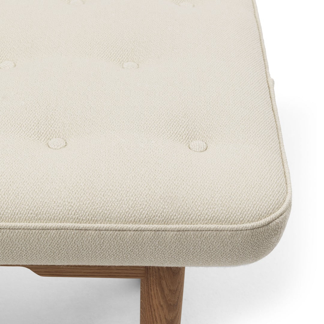 Cream-colored tufted cushion with a textured pattern on a natural wood base. Perfect for modern home decor.