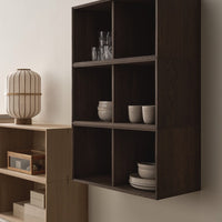Modern dark wood shelving unit with a minimalist design, featuring six compartments and neutral ceramic dishes.