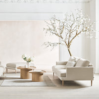 Light beige sofa with soft textures, paired with pale wood furniture against a neutral background and minimalistic decor.