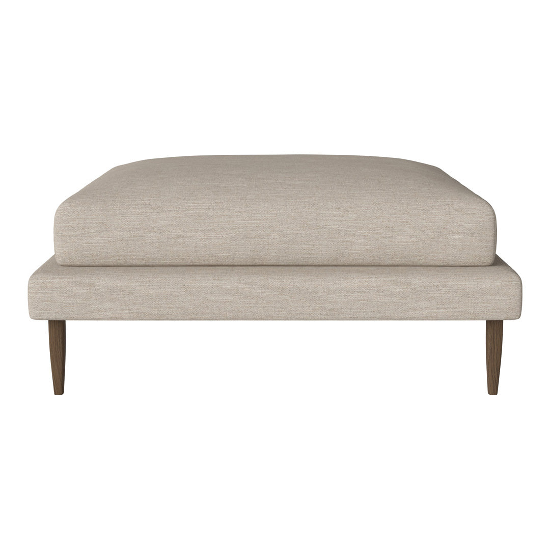 Beige upholstered ottoman with a smooth fabric finish and tapered wooden legs. Simple, modern design.