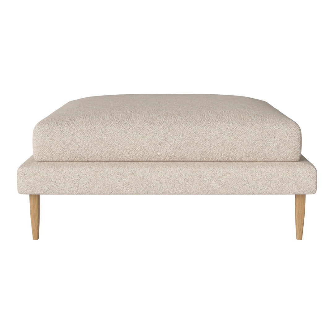 Beige upholstered ottoman with a subtle textured pattern and light wood legs. Stylish and modern design for any decor.