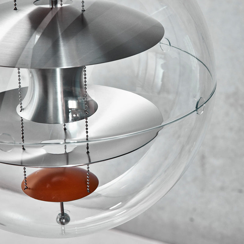 Modern pendant lamp with metallic silver, transparent glass, and a pop of orange accent color. Sleek and minimalist design.