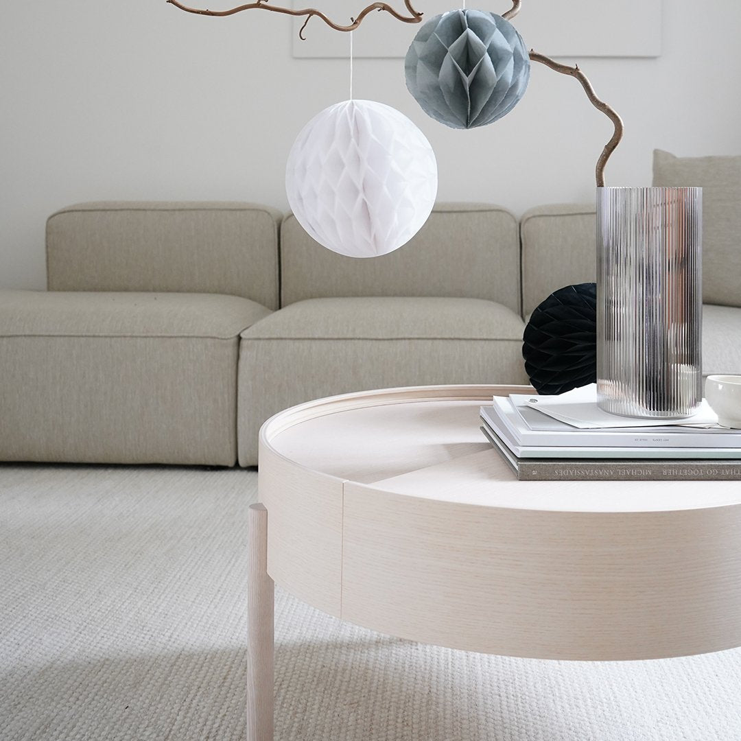 Elegant round coffee table in soft beige, surrounded by textured gray and white decor elements in a modern living room setting.