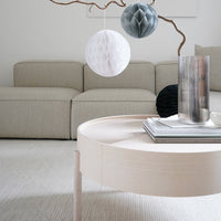 Elegant round coffee table in soft beige, surrounded by textured gray and white decor elements in a modern living room setting.