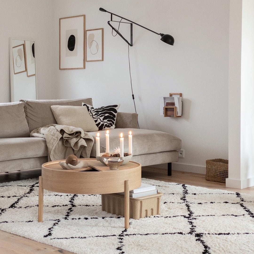 "Neutral-toned living room featuring a geometric black and white rug, wooden coffee table, and soft beige couch."