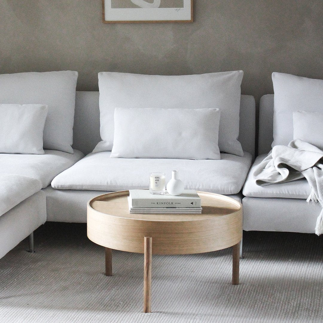 Modern white sectional sofa with plush cushions and a light wood coffee table against a neutral gray wall.