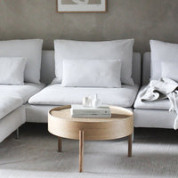 Modern white sectional sofa with plush cushions and a light wood coffee table against a neutral gray wall.