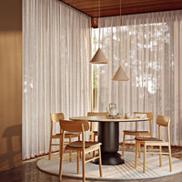 Sheer beige curtains with subtle texture, paired with light wood furniture against warm brown walls. Modern, earthy tones.