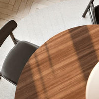 Brown wood grain tabletop with soft gray chair and light-colored rug, creating a modern, minimalist aesthetic.