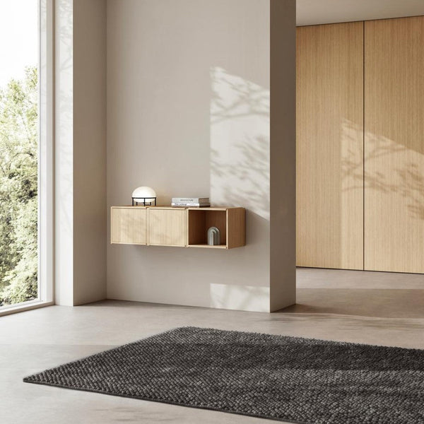 Modern interior featuring a light wood wall shelf, soft gray rug, and neutral walls, creating a calm, minimalist aesthetic.