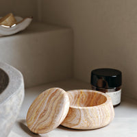 Natural stone bowl in warm tones of beige, cream, and subtle orange stripes, featuring a smooth, polished finish.