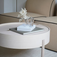 Neutral beige round coffee table with a sleek texture and minimalistic design, featuring simple white decor elements.