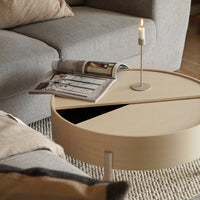 Modern round coffee table in soft beige, featuring a geometric split pattern, complemented by neutral tones in the decor.
