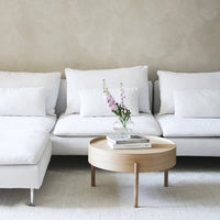 White sectional sofa with plush cushions, paired with a natural wood coffee table and light cream rug.