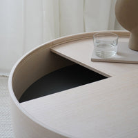 Light wood round coffee table with minimalistic design; contrasting black interior adds a modern touch.