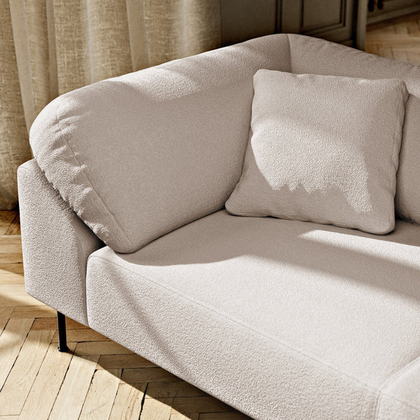 Light beige modern sofa with a textured fabric and matching soft square pillow, set on a wooden floor.